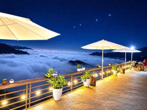 a patio with umbrellas and a view of the clouds at Xìu Homestay Tà Xùa in Bắc Yên