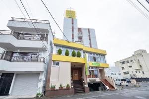 un edificio blanco y amarillo en una calle de la ciudad en Select Inn Shimada Ekimae en Shimada