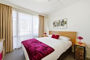 a bedroom with a large bed and a large window at City-Edge 1-Bed Apartment with Pool Access in Canberra