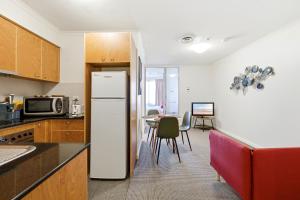 a kitchen with a refrigerator and a table with chairs at City-Edge 1-Bed Apartment with Pool Access in Canberra