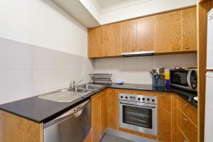a kitchen with wooden cabinets and a sink at City-Edge 1-Bed Apartment with Pool Access in Canberra
