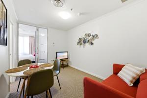 a living room with a table and a red couch at City-Edge 1-Bed Apartment with Pool Access in Canberra +18 photos
