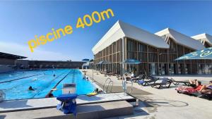 a large swimming pool with people in a building at Les Pâquerettes in Dinan