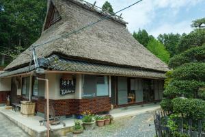 an old house with a thatched roof with plants at Tokuheian in Kyoto