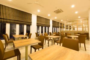 a restaurant with wooden tables and chairs and windows at Sparks Odeon Sukabumi, ARTOTEL Curated in Sukabumi