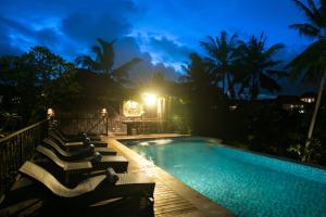 uma piscina à noite com um monte de cadeiras à volta em Tirta Arum em Ubud