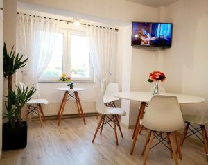 a living room with tables and chairs and a tv on the wall at Apartament Daria in Târgu Ocna