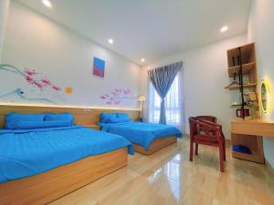 a bedroom with two beds with blue sheets and a chair at Mie's Homestay in Danang