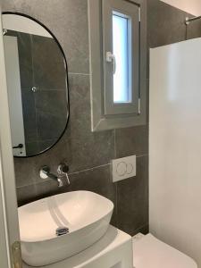 a bathroom with a white sink and a mirror at AiΘeria Suites Ios in Ios Chora