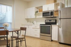 a kitchen with white cabinets and a table and a refrigerator at the blossom stay in Burnaby