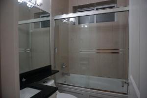 a bathroom with a glass shower with a toilet at the blossom stay in Burnaby