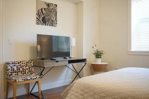 a bedroom with a desk with a television and a chair at the blossom stay in Burnaby