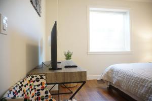 a bedroom with a bed and a desk with a television at the blossom stay in Burnaby