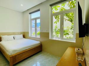 a bedroom with a bed and two windows at Tropical Homestay - Danang in Danang