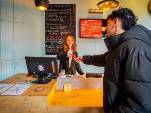a woman standing behind a cash register with a man at ibis Bordeaux Centre Gare Saint Jean Euratlantique in Bordeaux