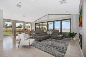 a living room with a couch and chairs and windows at Woodbine Waters Lakehouse in Yarrawonga