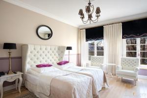 een witte slaapkamer met een groot wit bed met paarse kussens bij Dwór na Wolicy in Dębica
