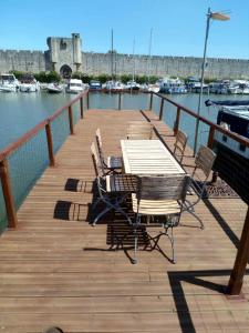 une terrasse en bois avec une table et des chaises à côté de l'eau dans l'établissement Péniche Poompui, à Aigues-Mortes