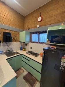 a kitchen with a refrigerator and a clock on the wall at Prakruthi Hill View 3BHK Entire Villa in Nandi