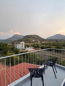 two chairs on a balcony with mountains in the background at Prakruthi Hill View 3BHK Entire Villa in Nandi