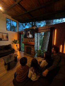 a group of people sitting in a living room watching a tv at Cabaña DAGO in Mazamitla
