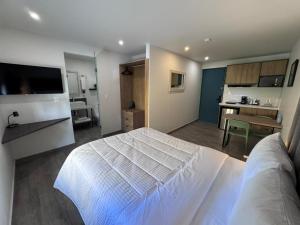 a bedroom with a white bed and a kitchen at San Jeronimo Suites in Monterrey