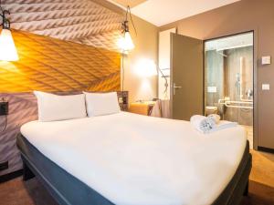a large white bed in a room with a bathroom at ibis Geneve Centre Lac in Geneva
