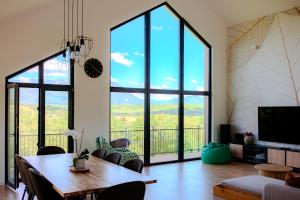 a living room with a table and chairs and large windows at Bran Villa - A-frame Orchard Hygge in Bran