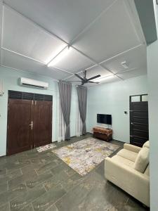 a living room with a couch and a tv at Homestay Anaza in Kampong Balai Maras