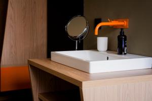 a white sink with a mirror on a wooden counter at ALPAMI Boutique Glockenbach in Munich