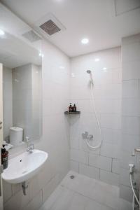 a white bathroom with a sink and a shower at Lavy at Anderson Pakuwon Mall in Surabaya +31 photos