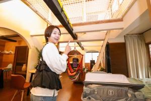 a woman standing next to a bed in a room at コテージくつろぎ in Tsuru 