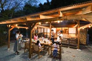 a group of people standing around a table in a backyard at コテージくつろぎ in Tsuru 