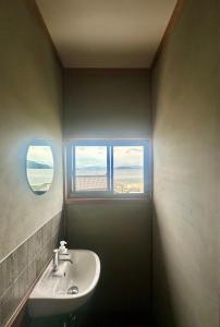 a bathroom with a sink and a window at 海辺の宿なみとけ in Shodoshima