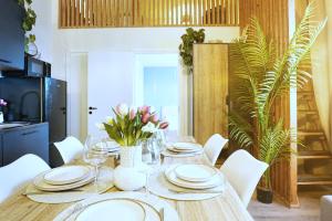 a dining room table with white plates and flowers on it at Cofy Rentals - old town, quiet area, air-conditioning, free parking, 24-7 express check-in-out, close to green parks, everything you need for living in Pärnu