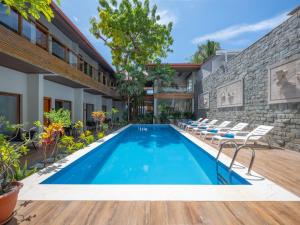 an outdoor swimming pool with chairs and a building at Kaani Village & Spa - Stay 3 Nights and Save 20 Percent on Spa and 10 Percent on Dining Until 31 October 2026 in Maafushi