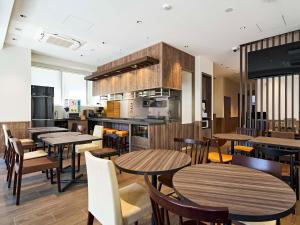a restaurant with tables and chairs and a kitchen at TORANOMONHOLIC Hotel in Tokyo