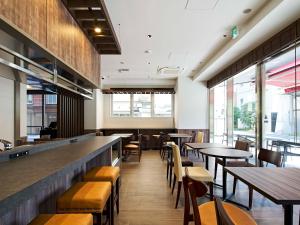 a restaurant with tables and chairs and windows at TORANOMONHOLIC Hotel in Tokyo