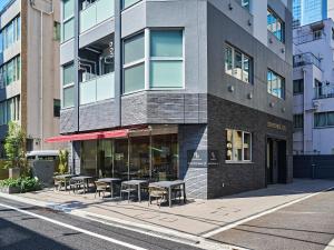 a building with tables and chairs on a city street at TORANOMONHOLIC Hotel in Tokyo