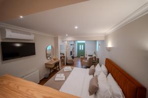 a bedroom with a large white bed and a living room at Leon Suites Nemea in Neméa