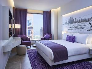 ein Hotelzimmer mit einem großen Bett und einem Stuhl in der Unterkunft Mercure Dubai Barsha Heights Hotel Suites And Apartments in Dubai