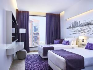 ein Hotelzimmer mit zwei Betten und einem großen Fenster in der Unterkunft Mercure Dubai Barsha Heights Hotel Suites And Apartments in Dubai