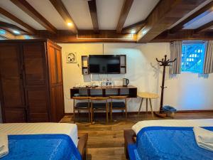 a bedroom with two beds and a desk with a tv at NamKhan Riverside in Luang Prabang