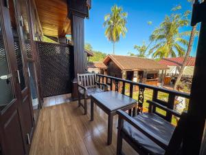 a porch with benches and a table on a balcony at NamKhan Riverside in Luang Prabang