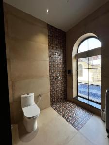 a bathroom with a toilet and a window at The Benjamins Pool Villa in Jodhpur