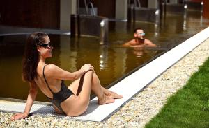 a woman in a bathing suit sitting in a swimming pool at Hotel Galeria Thermal Bešeňová in Bešeňová