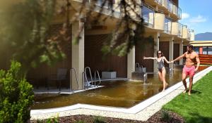 two people walking in the water outside of a building at Hotel Galeria Thermal Bešeňová in Bešeňová +80 photos