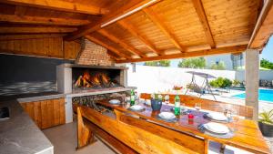 a patio with a table and an outdoor fireplace at Villa Rab Paradise pool by Villas Guide in Lopar