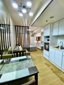 a kitchen and a living room with a couch and a table at Cozyluxe at Pine Suites Tagaytay in Kaybagal