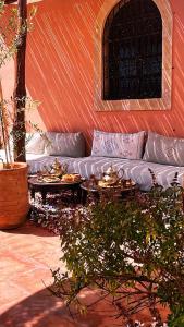 a couch sitting on a patio with two tables at Riad Aïcha Addi Pool & Hammam in Essaouira
